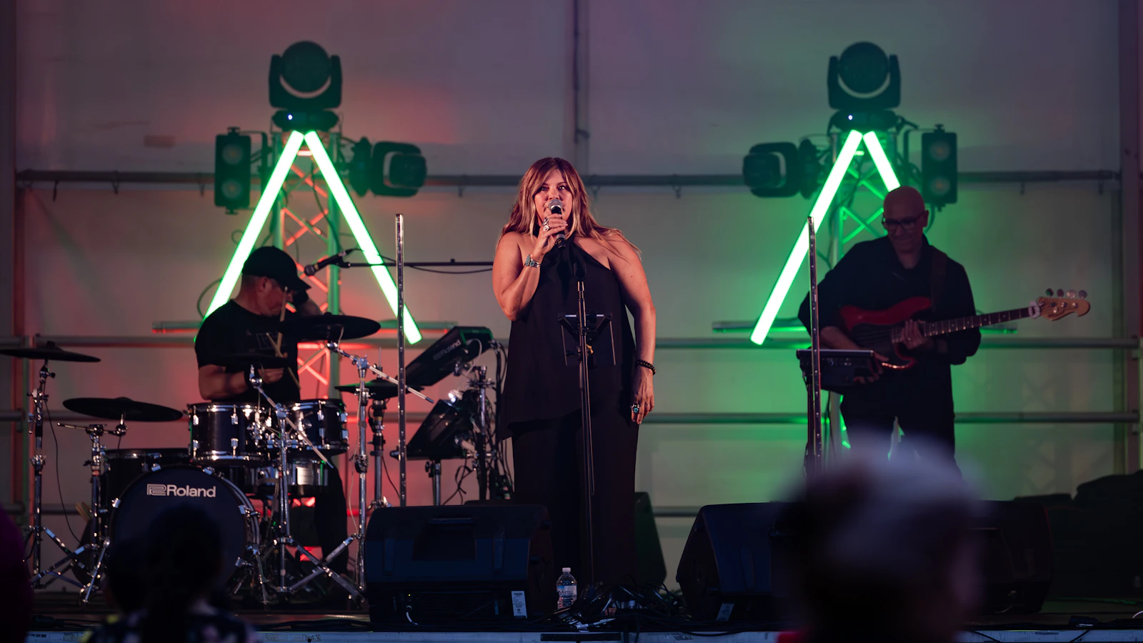 Musicians performing together on a stage under colorful lights