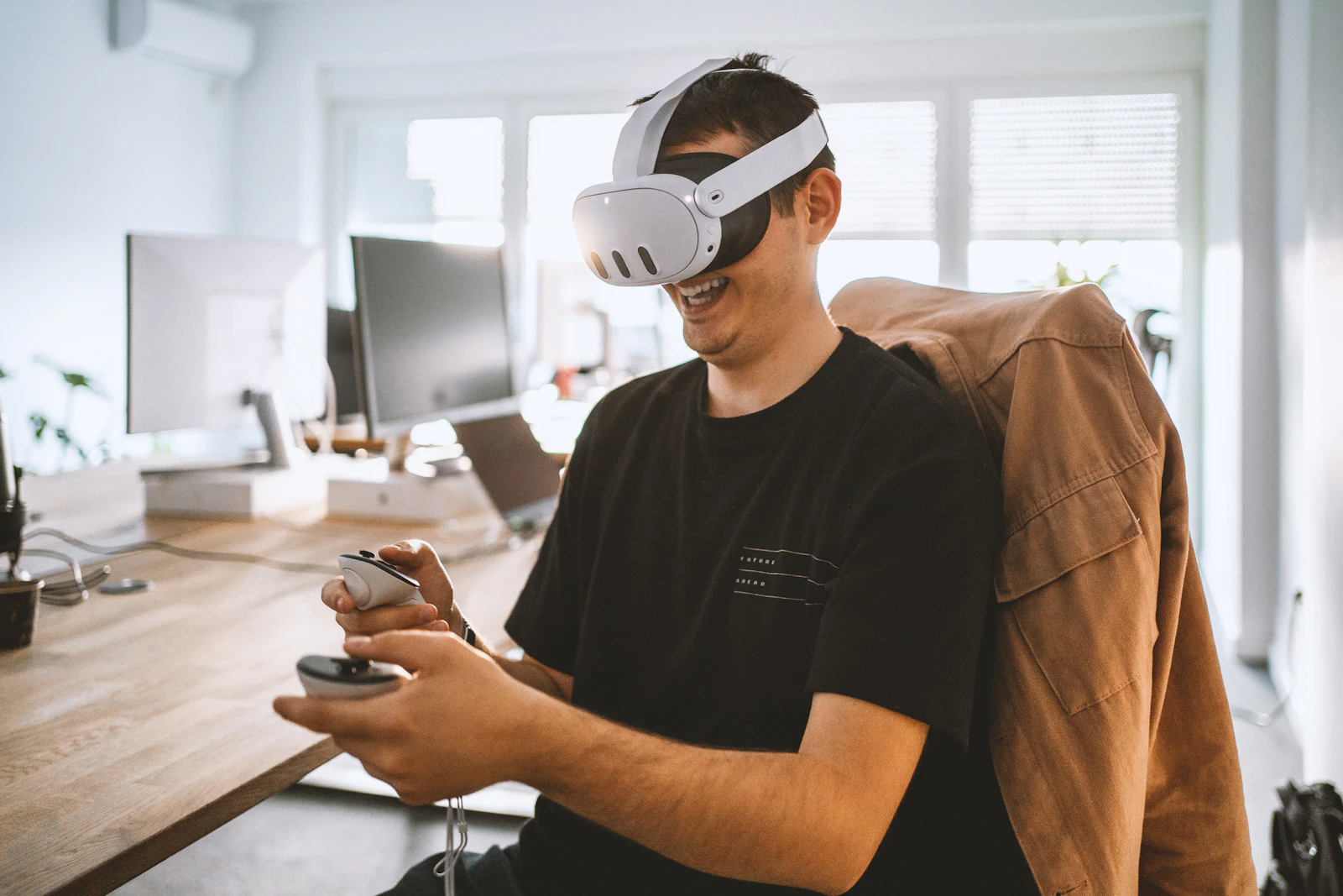 A person exploring a mixed reality headset with controllers at a desk